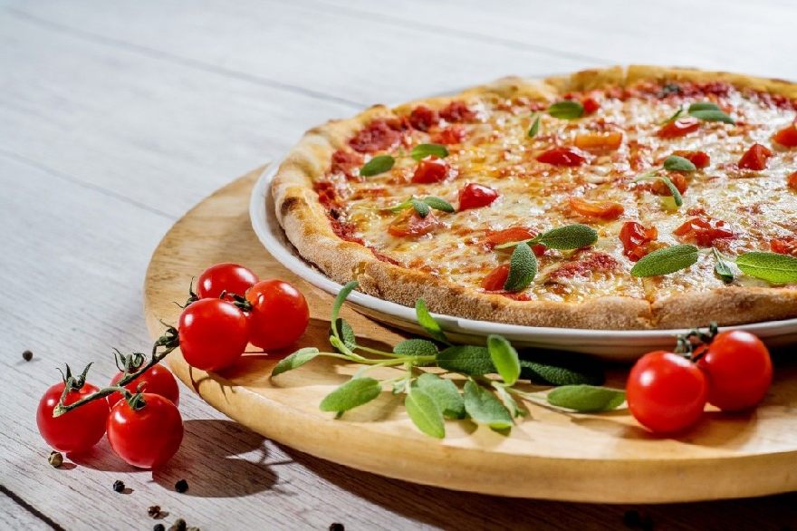 Leckere Pizza auf einem Teller schön auf dem Tisch angerichtet ähnlich wie bei der Pizzeria Alba mit sehr guten Essen wie Pizza und Pasta Nudeln mit Lieferservice in Duisburg.